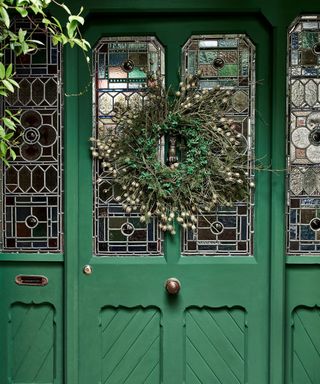Green front door with traditional stain-glass and christmas wreath decoration