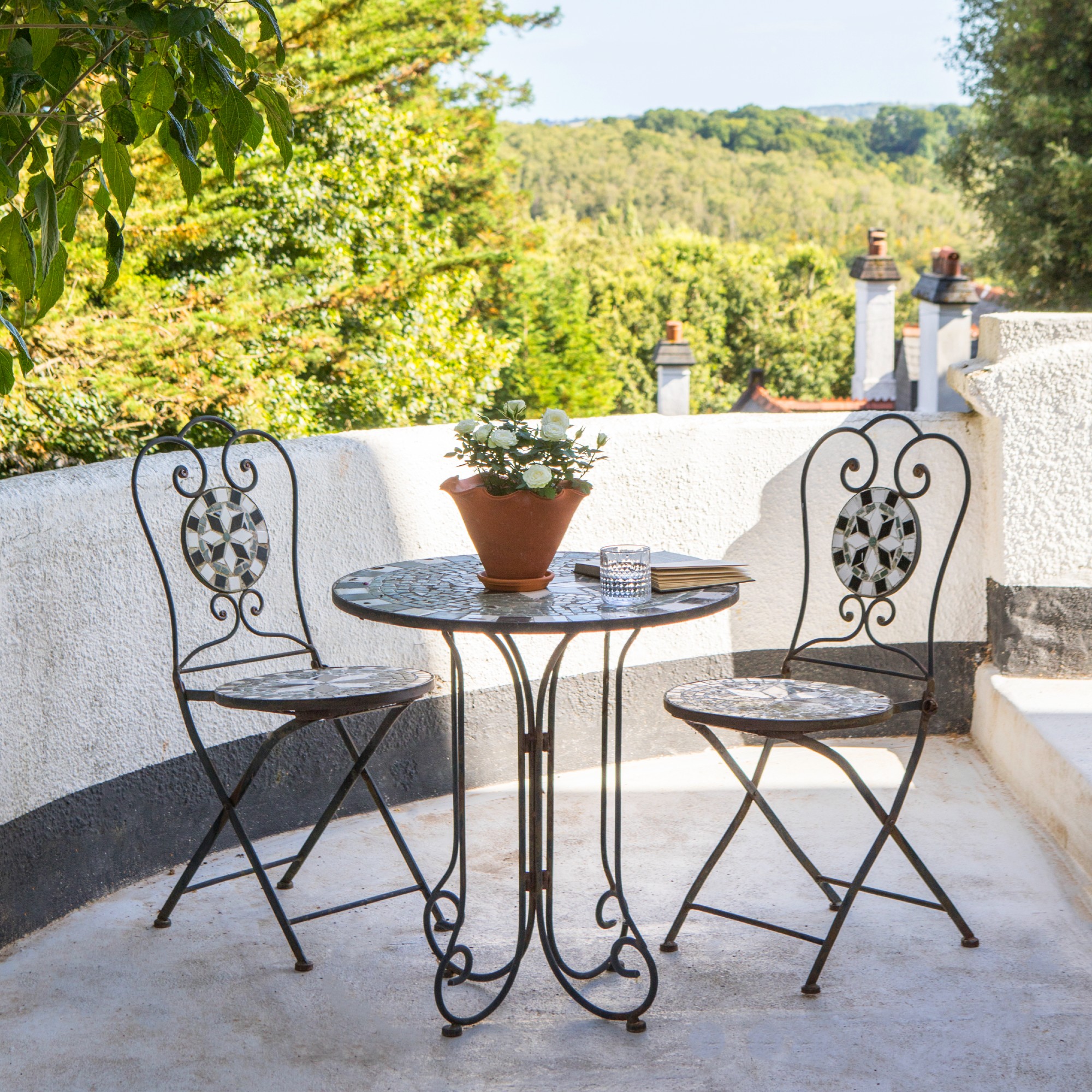 A sunny patio with a mosaic-style curved bistro set
