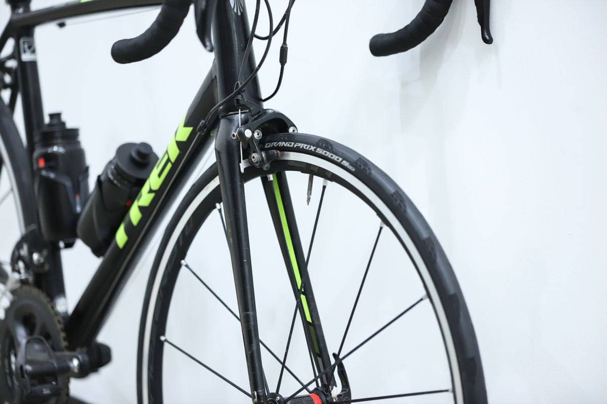 A black and yellow Trek Emonda ALR sits against a white wall