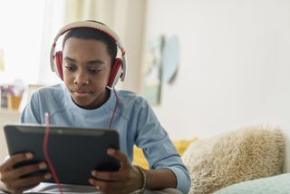 Boy in headphones learning from home with broadband discount on tablet
