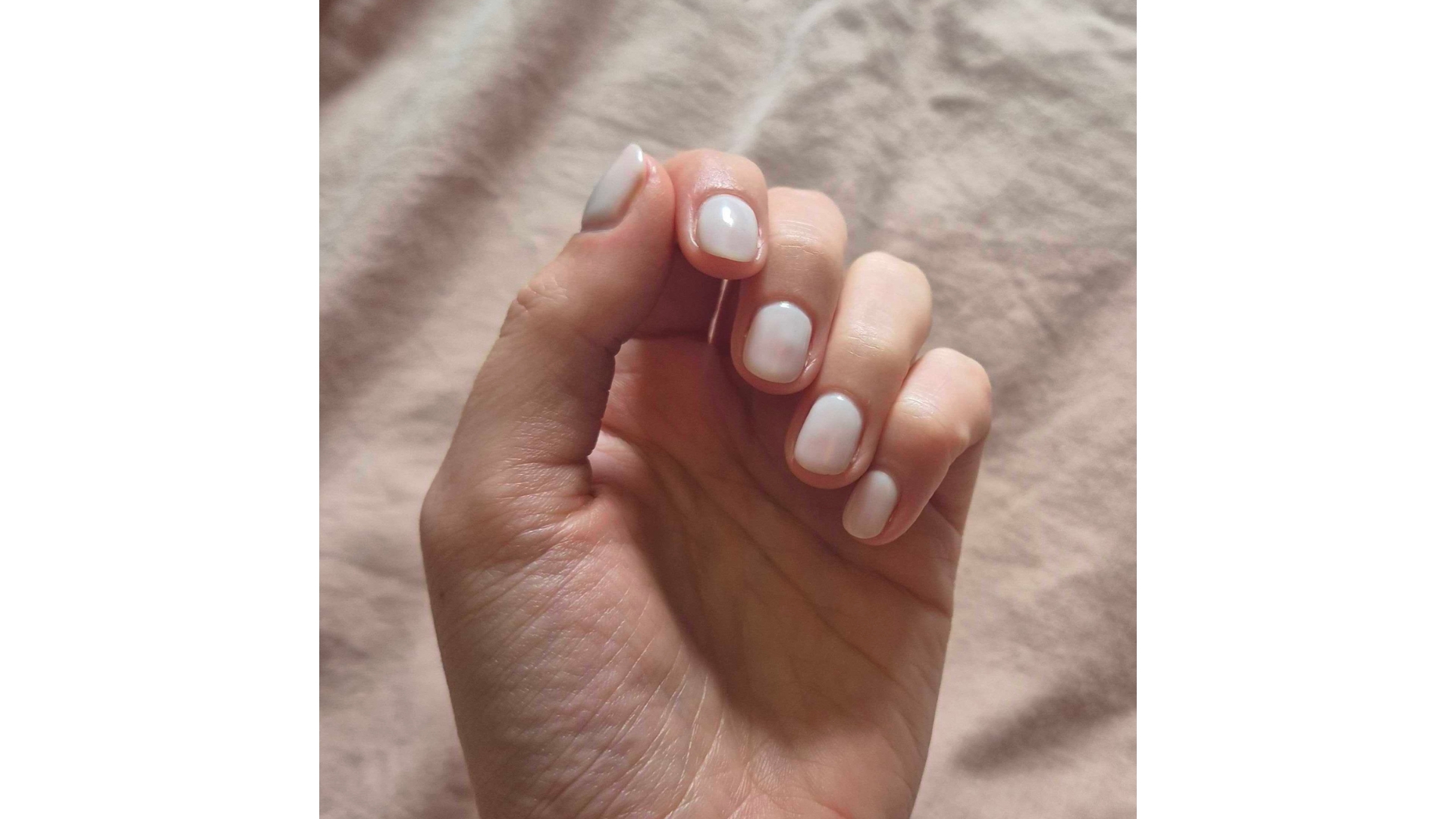 Image of digital beauty writer, Naomi Jamieson's hand curled with short square nails, painted with sheer pinky white nail polish