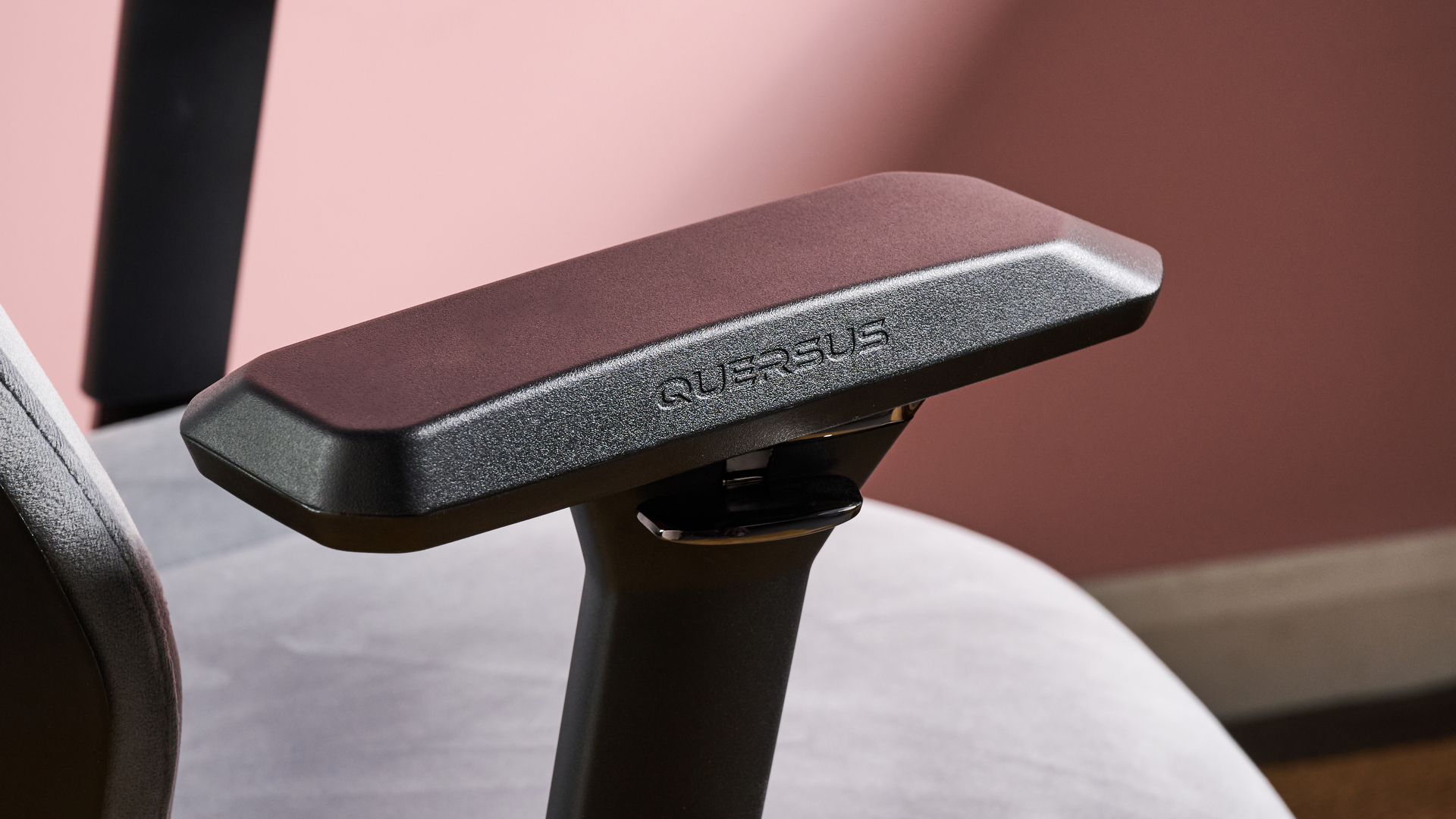 Close-up of right arm rest on Quersus ICOS.2 with pink wall in background