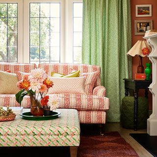 Living room with sofa, footstool and curtains in small-scale printed fabrics