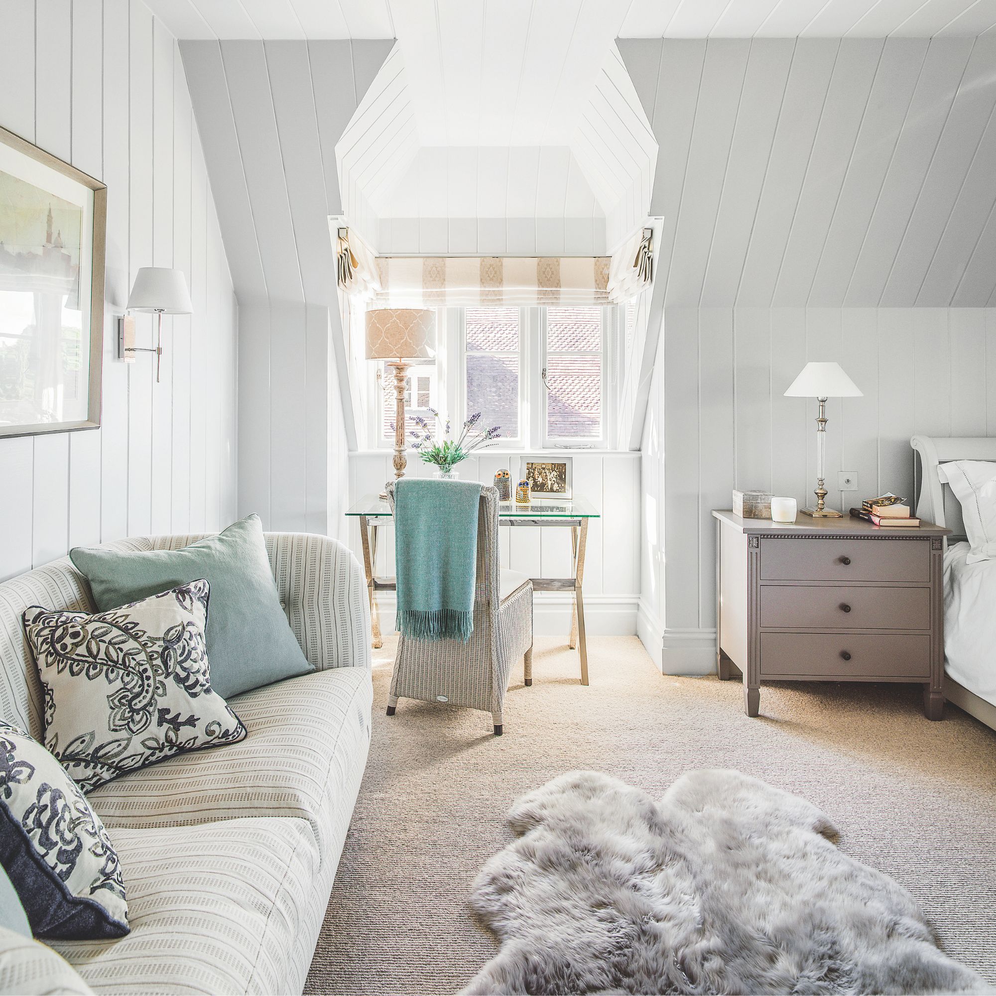 Bedroom with a sofa and a dressing table at the back of the room, with wool carpet and a fluffy rug