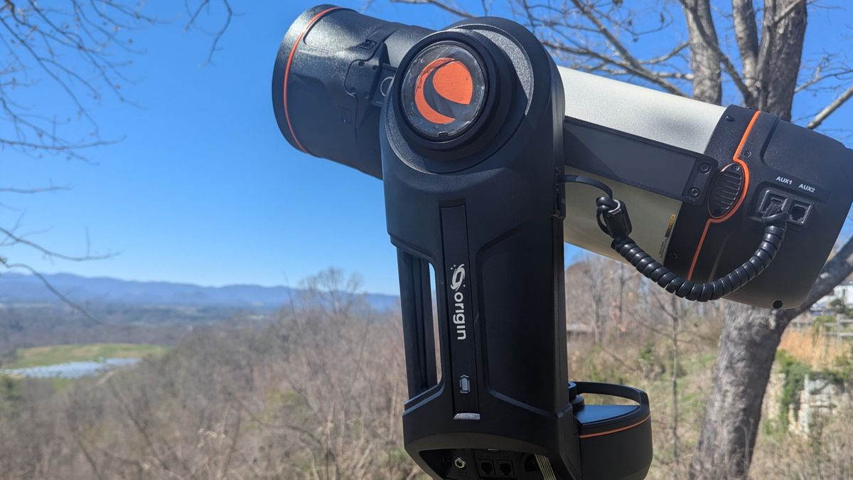 a white telescope on a grassy mountaintop under a clear blue sky