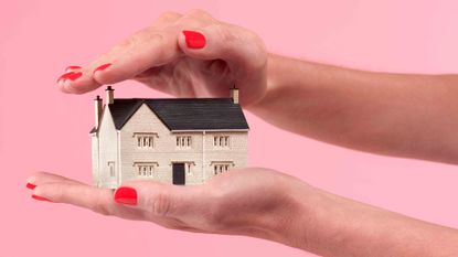 two hands holding a scale model house