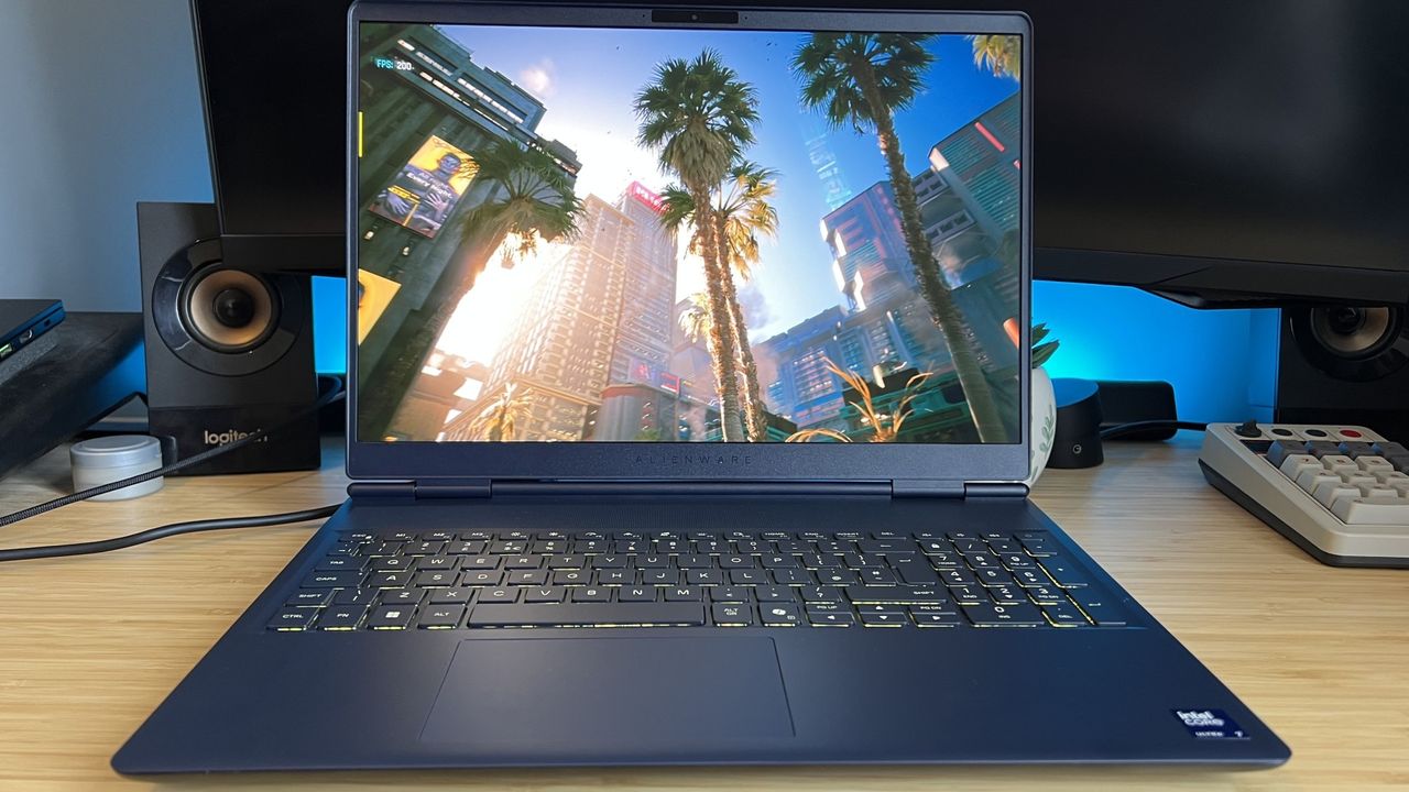 Alienware 16X Aurora 2026 gaming laptop on a wooden desk running Cyberpunk 2077 benchmark