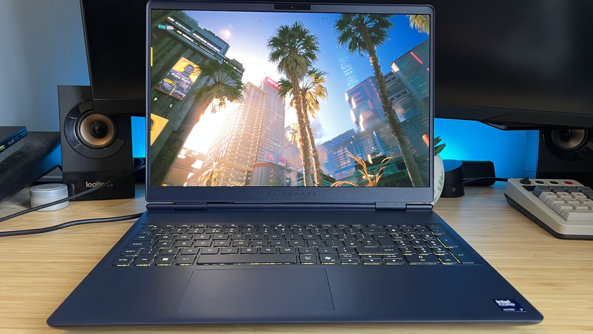 Alienware 16X Aurora 2026 gaming laptop on a wooden desk running Cyberpunk 2077 benchmark