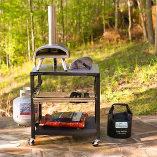 Black wheeled frame with pizza oven on top in outdoor setting