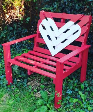A homemade pallet chair painted in red outdoor wood paint
