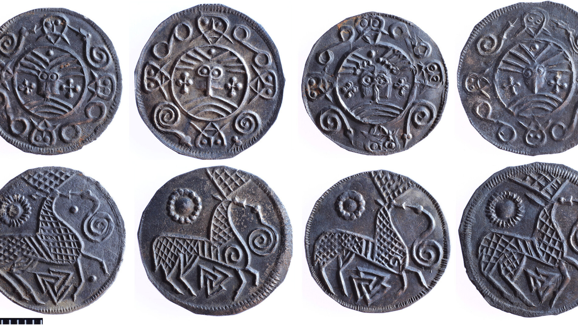 A close up of a series of round silver coins with various designs on them against a white background.