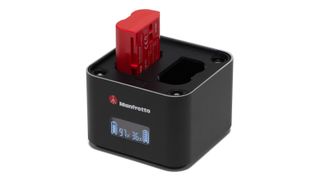 Manfrotto ProCube charger, with a red Manfrotto battery inserted, sitting on a white surface