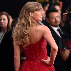 Taylor Swift at the 2025 Grammys wearing a red strapless dress with her back to the camera