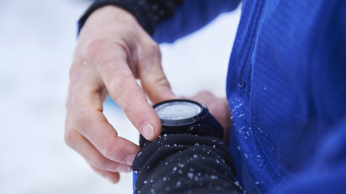 Close-up of skier&#039;s hands checking sports watch in the snow