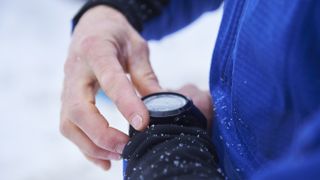Close-up of skier's hands checking sports watch in the snow