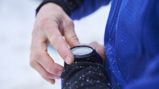 Close-up of skier&#039;s hands checking sports watch in the snow