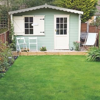 Garden with grass and a summer house/shed at the bottom of the garden