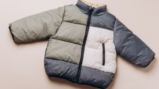 Olive green, cream, and navy puffer jacket on neutral background