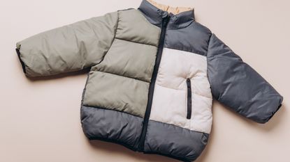 Olive green, cream, and navy puffer jacket on neutral background