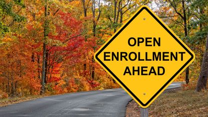 A sign by a road says open enrollment ahead.