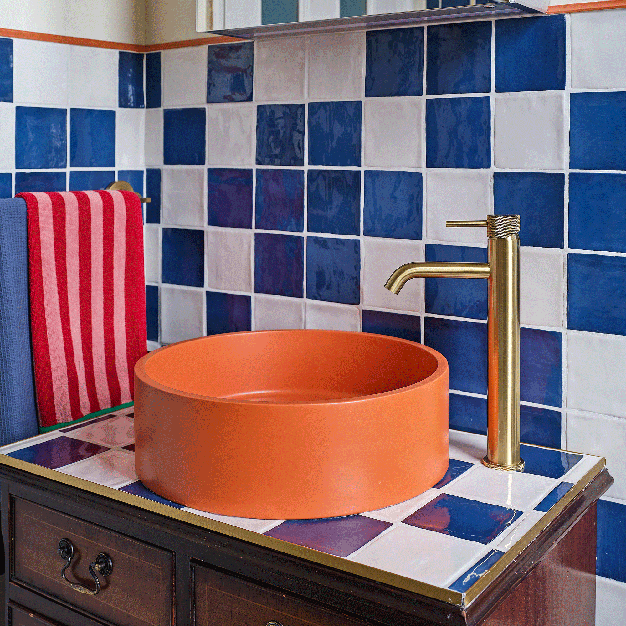 an orange and blue bathroom with a bright orange contemporary style basin on a vanity made from a vintage chest of drawers