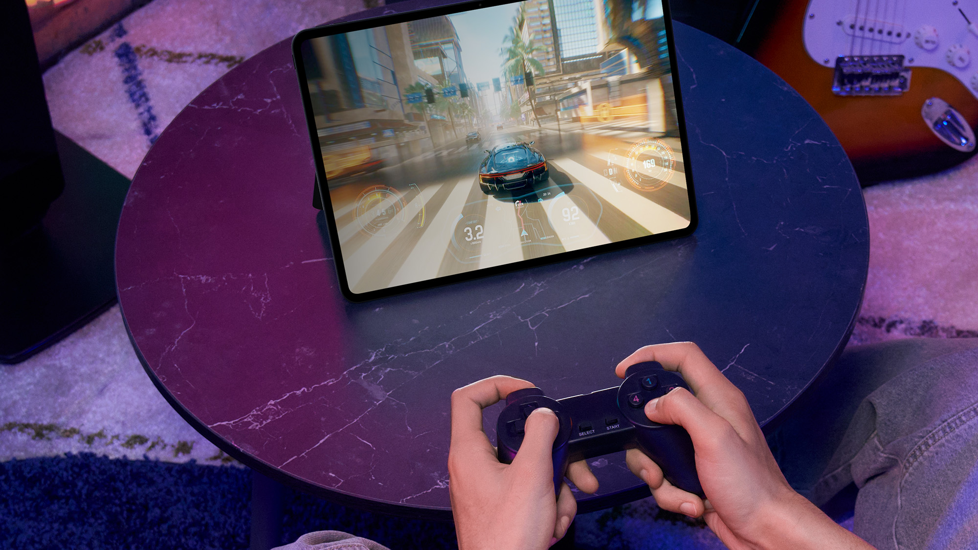 OnePlus Pad 3 lifestyle image on table with hands holding videogame controlling playing a racing game on the tablet