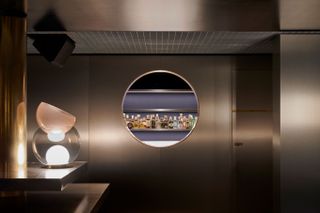 Glimpse of cocktail bar through round porthole in wall