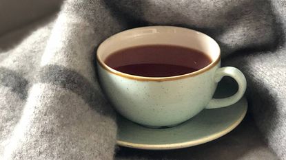 A cup of coffee wrapped up in a blanket, sleep & wellness tips