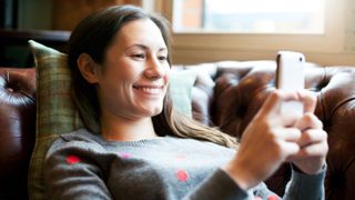 Woman smiling lying down on the sofa on the phone with a friend