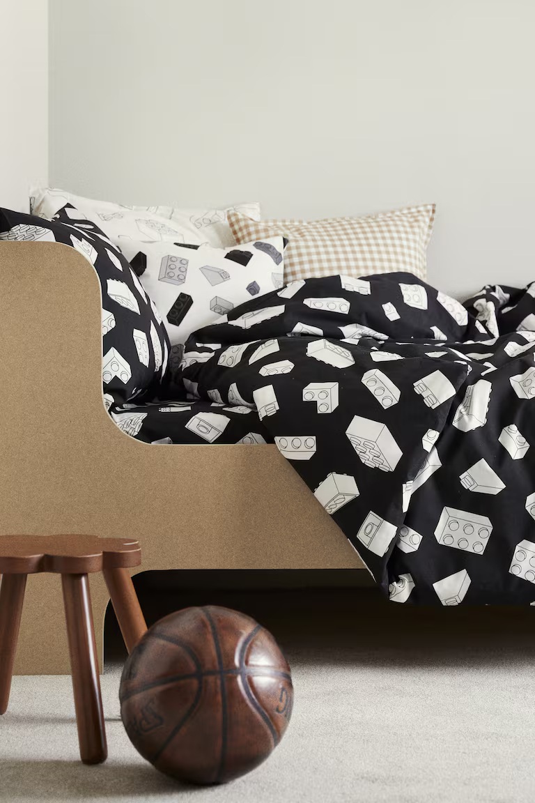 kids bedroom with LEGO-themed black and white bedding, timber bed, timber stool, and leather basketball