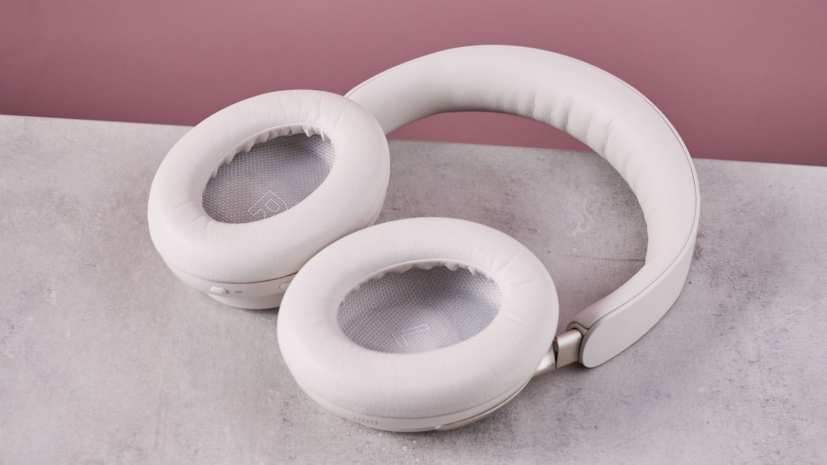 Bose QuietComfort Ultra Headphones on a gray surface with a pink background, showing the inside of the earcups