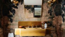 Jewel-toned guest bathroom featuring botanical mural wallpaper and brass wall sconces