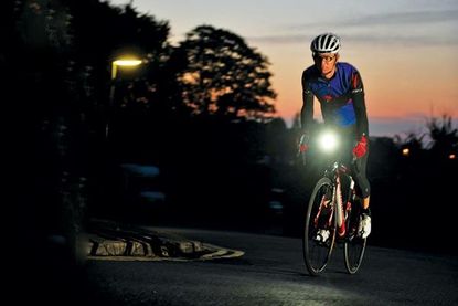 Male cyclist riding his bike in the dark with red sunset sky