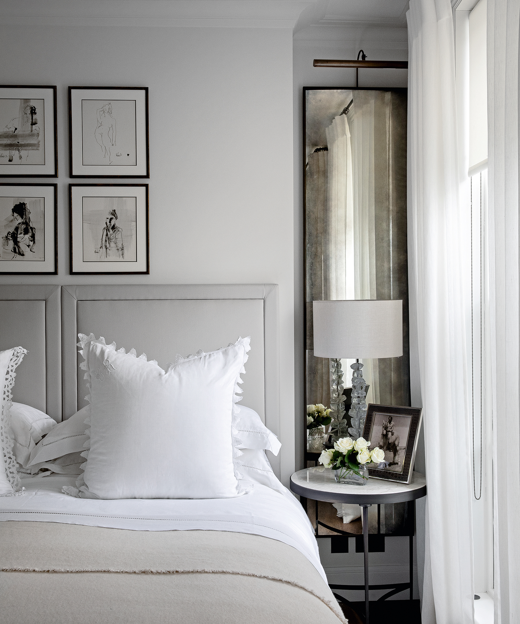 A grey bedroom idea with pale grey headboard, tarnished mirror and white linen