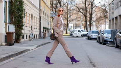  Influencer and model Marlies Pia Pfeifhofer wearing a 70s suit by Tory Burch, a white turtleneck pullover by Allude, sunglasses by Lanvin, ring and earrings by Ole Lynggaard, a brown bag by Louis Vuitton and purple high heel booties by Lola Cruz during a street style shooting on January 27, 2022 in Munich, Germany.