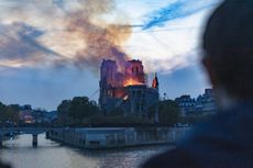 an image of Notre Dame burning as a man looks on