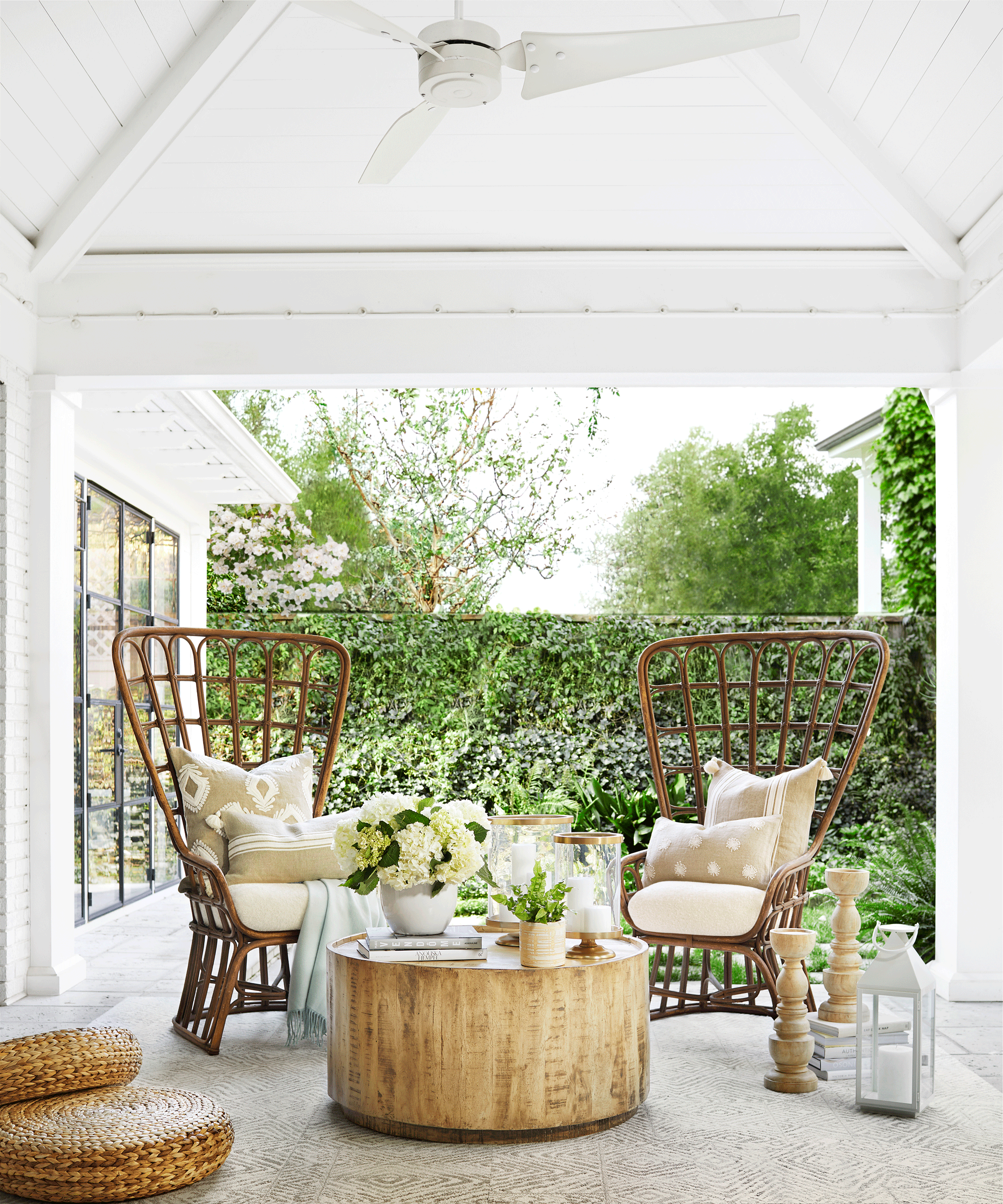Natural porch style with rustic materials, peacock style cane chairs, and wooden round coffee table.