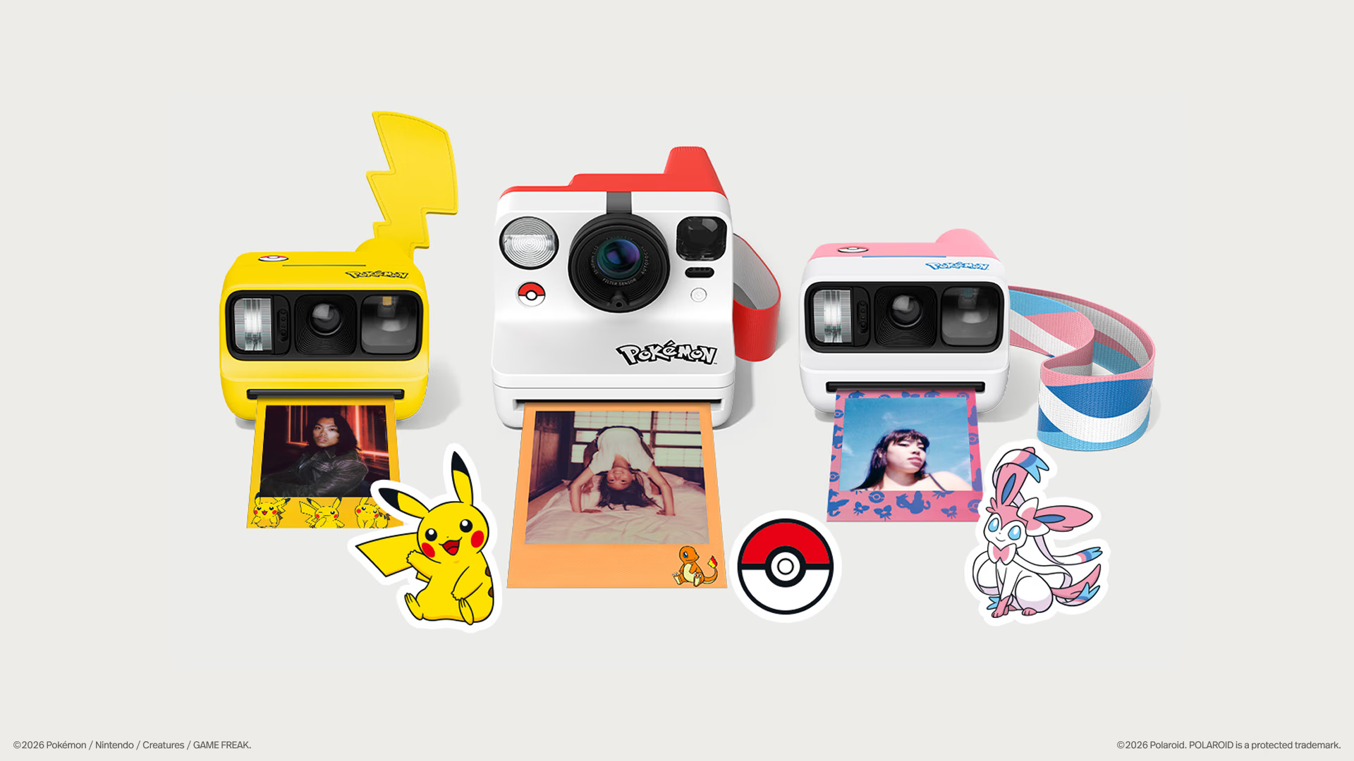 Three Pokemon-themed Polaroid cameras in a row on a plain background, with Pokemon and a Poke Ball beside them