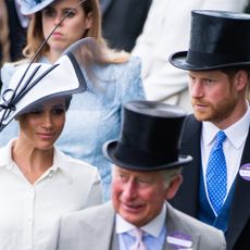 Meghan Markle wears a white dress with a matching hat, while Prince Harry and King Charles wears suits and top hats at Royal Ascot in 2018