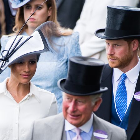 Meghan Markle wears a white dress with a matching hat, while Prince Harry and King Charles wears suits and top hats at Royal Ascot in 2018