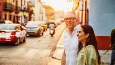 Smiling couple walking on city streets at sunset 
