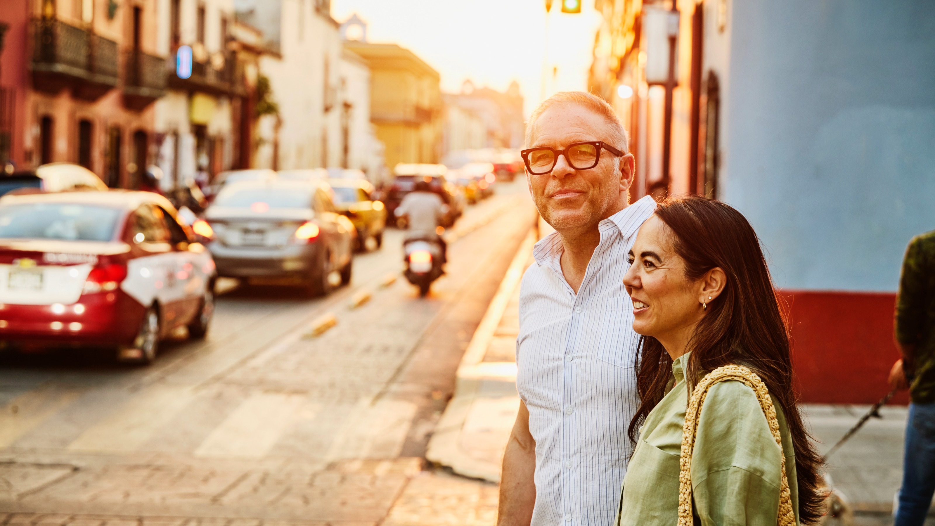 Smiling couple walking on city streets at sunset