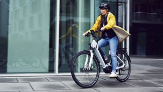 A woman in a yellow coat riding a hybrid e bike