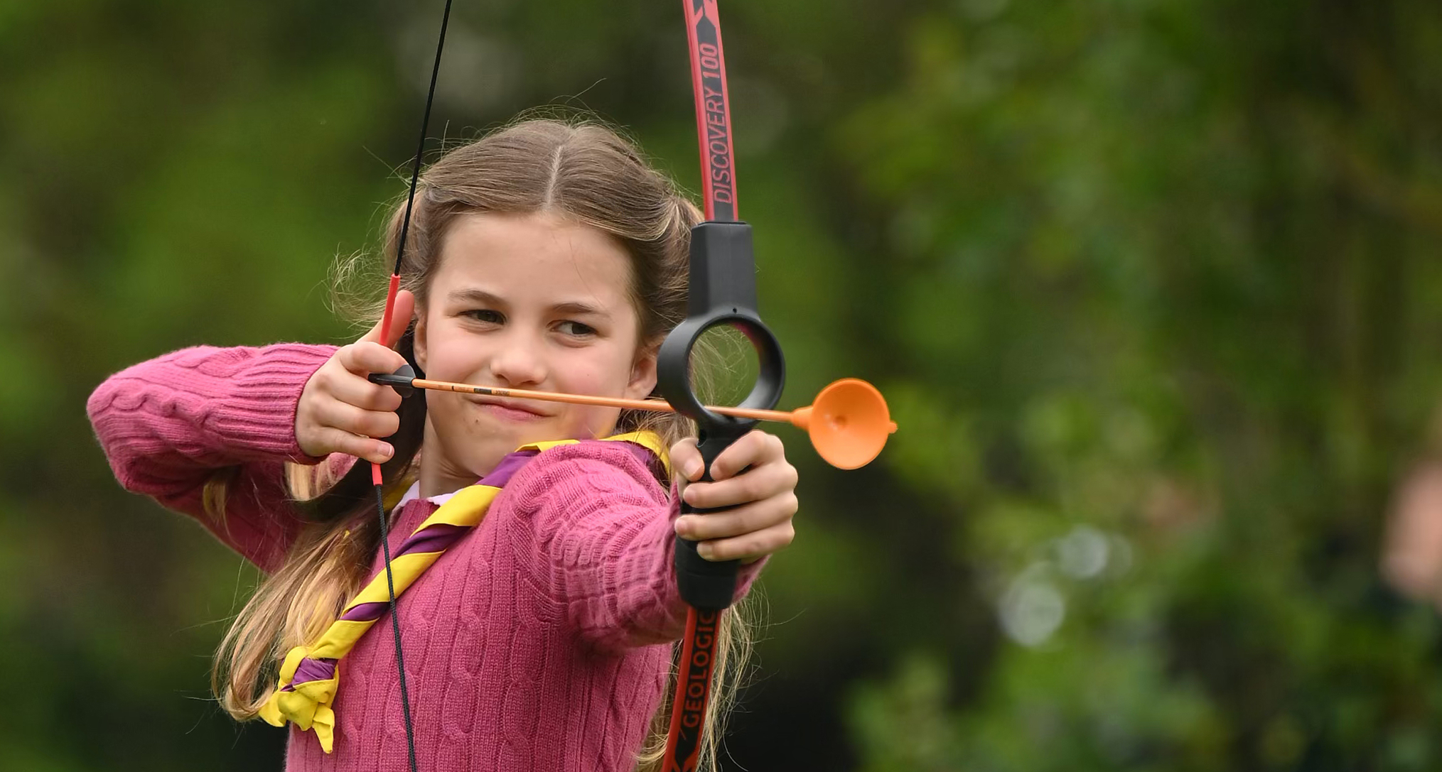 Princess Charlotte wearing a pink sweater playing archery