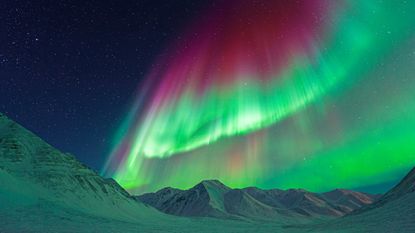 The northern lights shine above mountains near Atigun Pass, Dalton Highway, Alaska.
