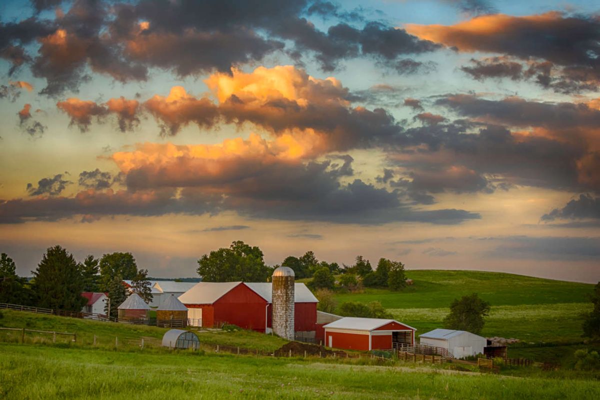 Red barn and other farm buildings nestled in rolling hills