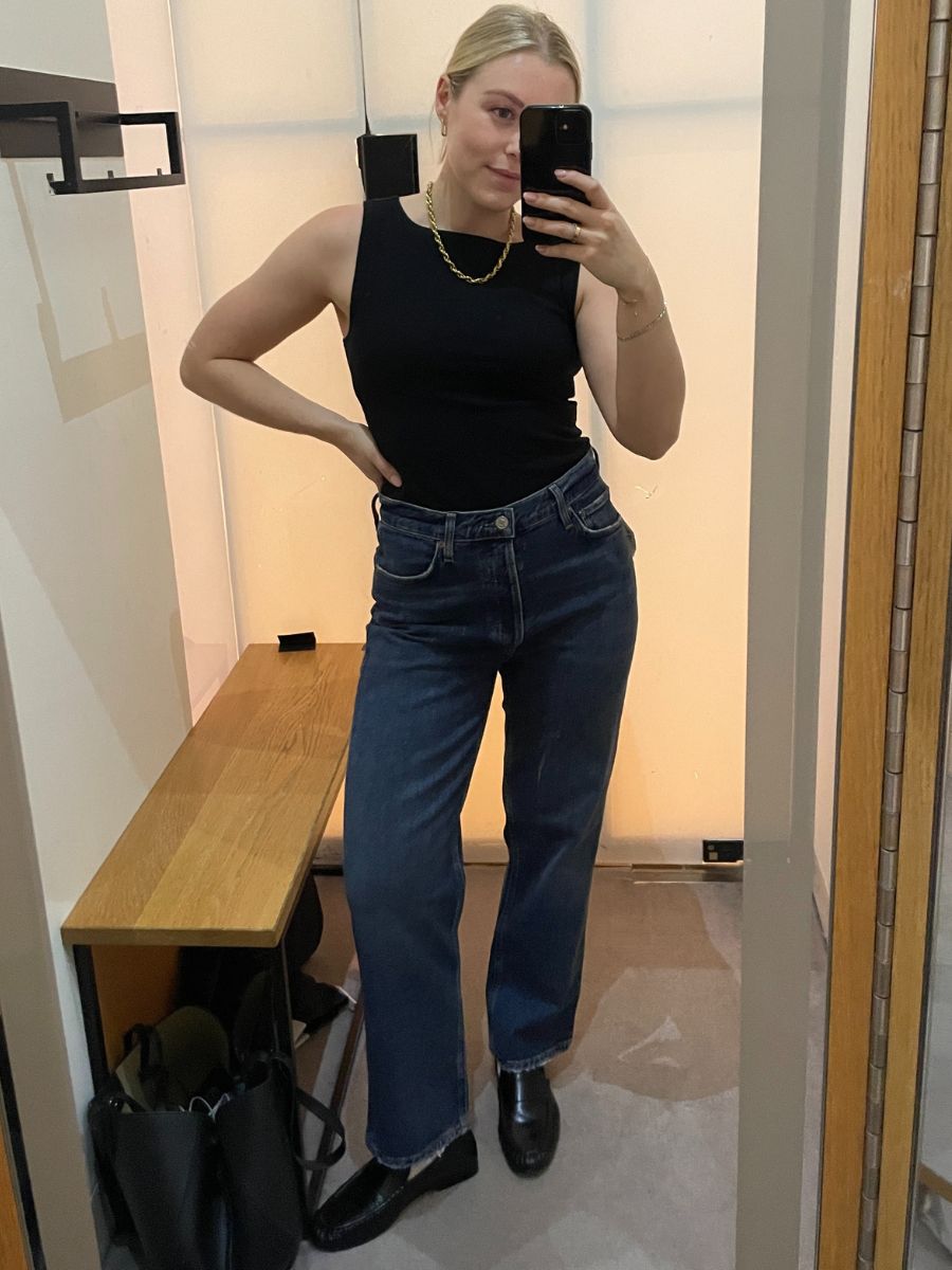 Woman wears black top, blue jeans and black loafers