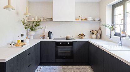 scandi style kitchen with white walls and worktops and dark painted cabinetry below