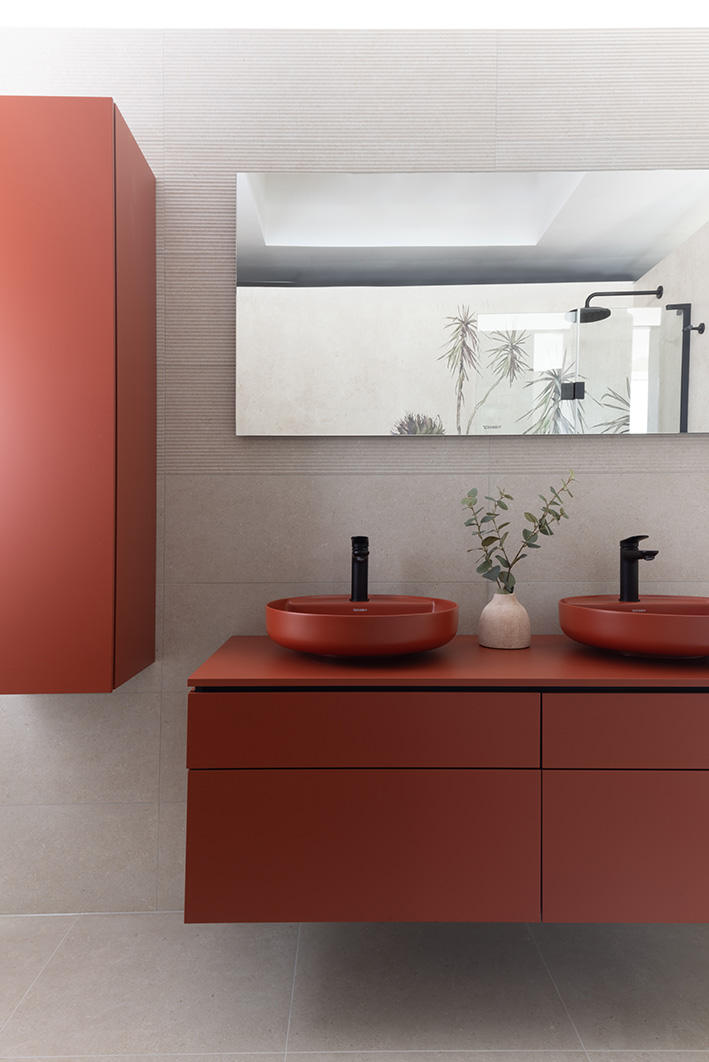 Grey tiled bathroom with red vanity and matching cabinets, and matching red double sink.