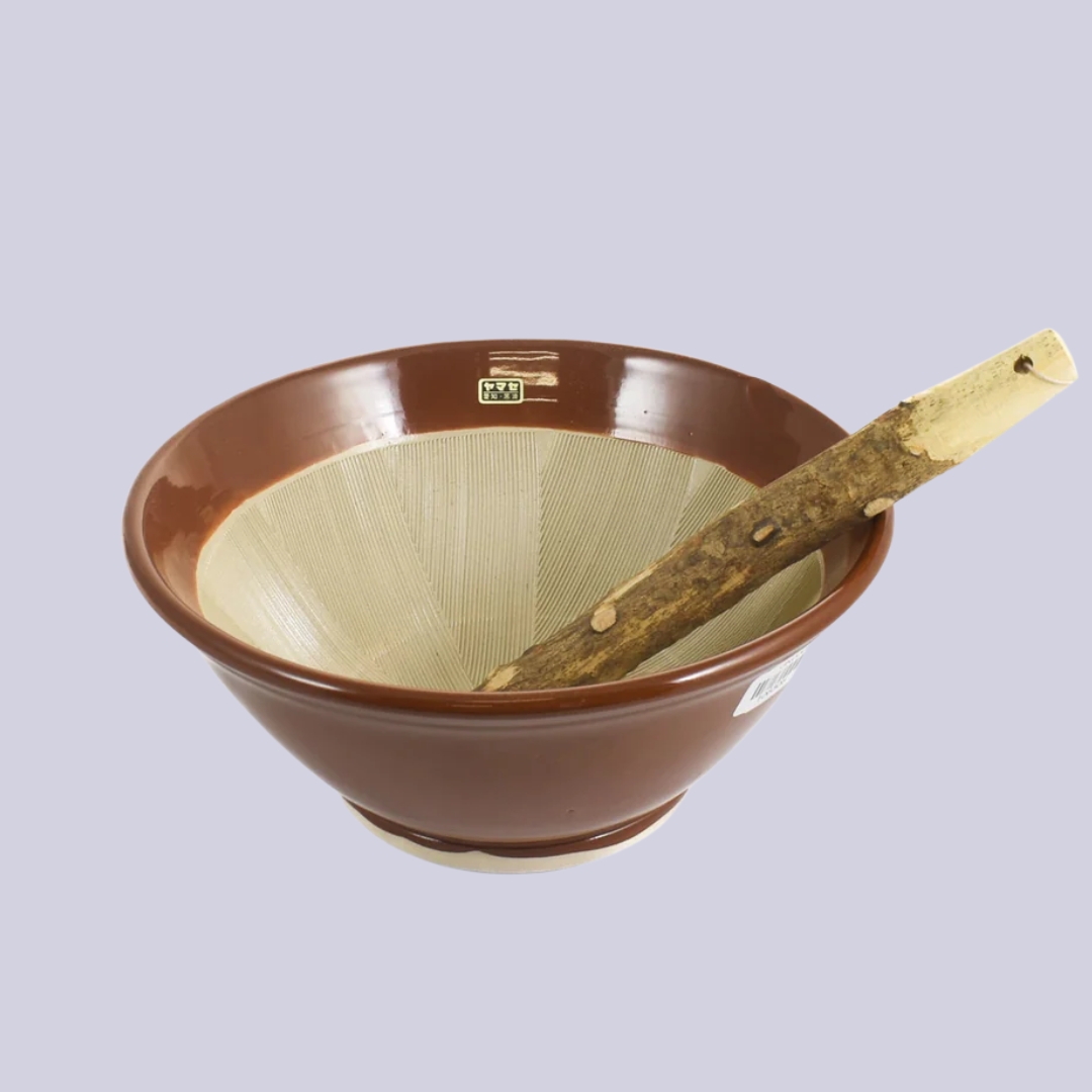 A Large Suribachi Mortar &amp;amp; Pestle ain brown and beige sits against a pale lilac background.